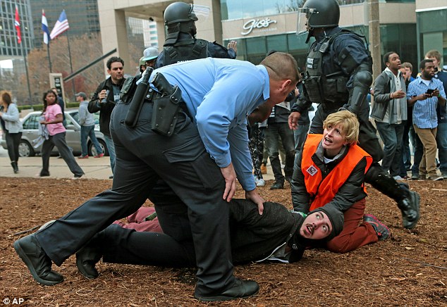 Help: A clergy member assists a protester as he is arrested and left on the ground near to the St. Louis Rams and Oakland Raiders game on Sunday