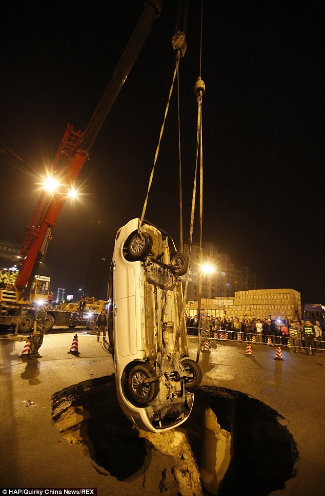 The largely undamaged car is hoisted out of the sinkhole giving a clear idea of just how big the hole was; Mr Hsiao plans to sue local highway officials claiming the road had been dug up and resurfaced just weeks before the incident, but they say the sinkhole was caused by heavy rain and a faulty drain