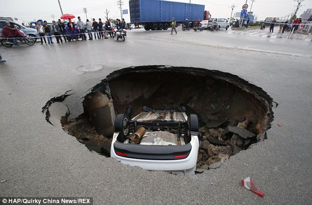 Wai Hsiao's car can be seen upside down inside the 20ft deep sinkhole that swallowed his car as he drove to work in Quanzhou, a city in south-eastern China's Fujian province