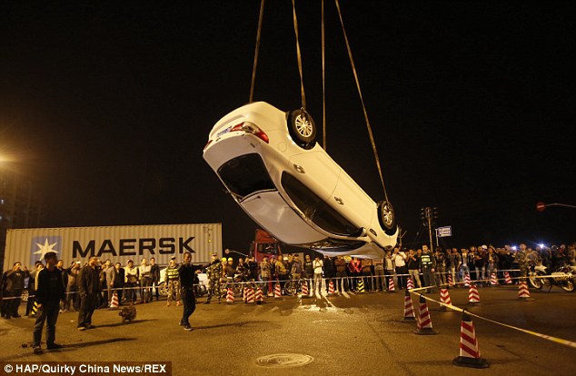 Crowds gather around as the car is removed; Mr Hsiao said no one came to his rescue after his car got stuck; when he scrambled from the hole people were busy taking pictures of the incident, he said