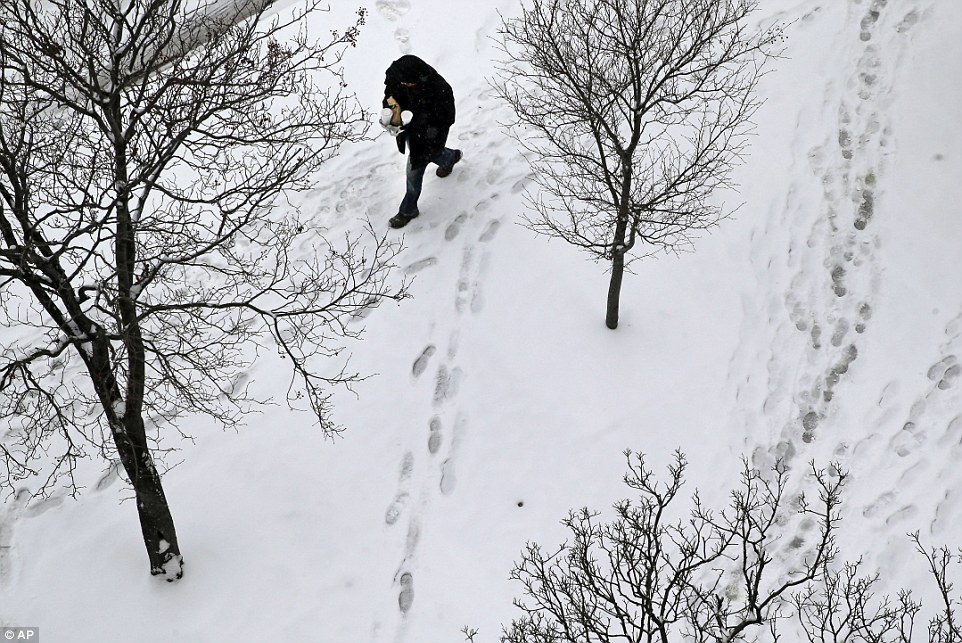 A man walks on a snow-covered sidewalk, Tuesday in Baltimore. The National Weather Service says snowfall totals could reach 4 to 6 inches in the Washington suburbs and 3 to 5 in the Maryland mountains