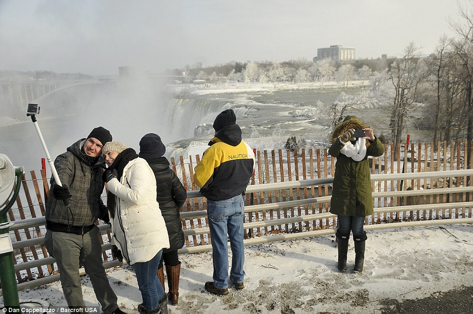 Iconic: Tourists shoot photos of a frozen landscape on Goat Island overlooking Niagara Falls as arctic conditions grip the Northeastern United States