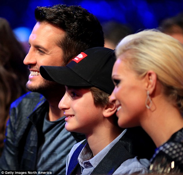 Til (pictured center) sits between Country superstar Luke Bryan and his wife, Caroline, at the American Country Countdown Awards in mid-December. Til is now living with the couple following the death of his father, Lee