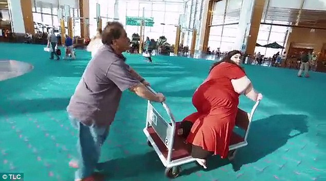 Resourceful: Her father Abe (left) manages to find an oversized luggage cart, and wheels her through the airport on that instead