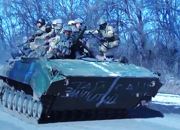 Parade: Journalists were lined up alongside the road in as the tank came rumbling past, packed with soldiers who were clinging to the top supposedly ready for battle