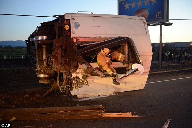 A firefighter crawls out of a derailed passenger train carriage at the scene of a Metrolink accident today