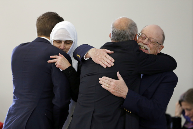 Embraced by community: Ed, right,  and Paula Kassig, left center,  parents of Peter Kassig, are hugged by Tory Stempf, right center, and his son Morgan Stempf before funeral prayers