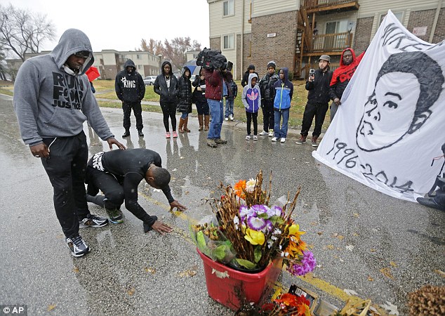 Devastated: Daily tributes are paid to shrines for Michael Brown who allegedly had his hands up when he died