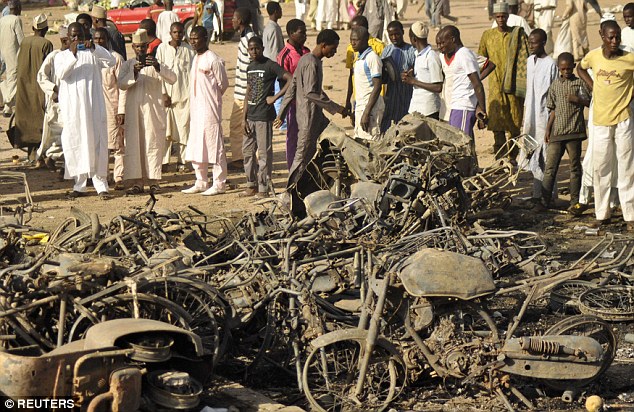 A crowd looks at the wreckage left after multiple bombings at Grand Mosque in Kano. At least 120 are feared dead and 270 injured after gunmen and suicide bombers attacked the mosque today during Friday prayers