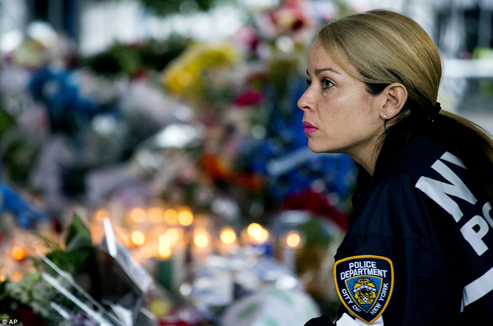 Grief: NYPD Lieutenant Tanisha Gurley is seen above with a single tear running down her face as she kneels in front of a makeshift memorial for slain officers Rafael Ramos and Wenjian Liu