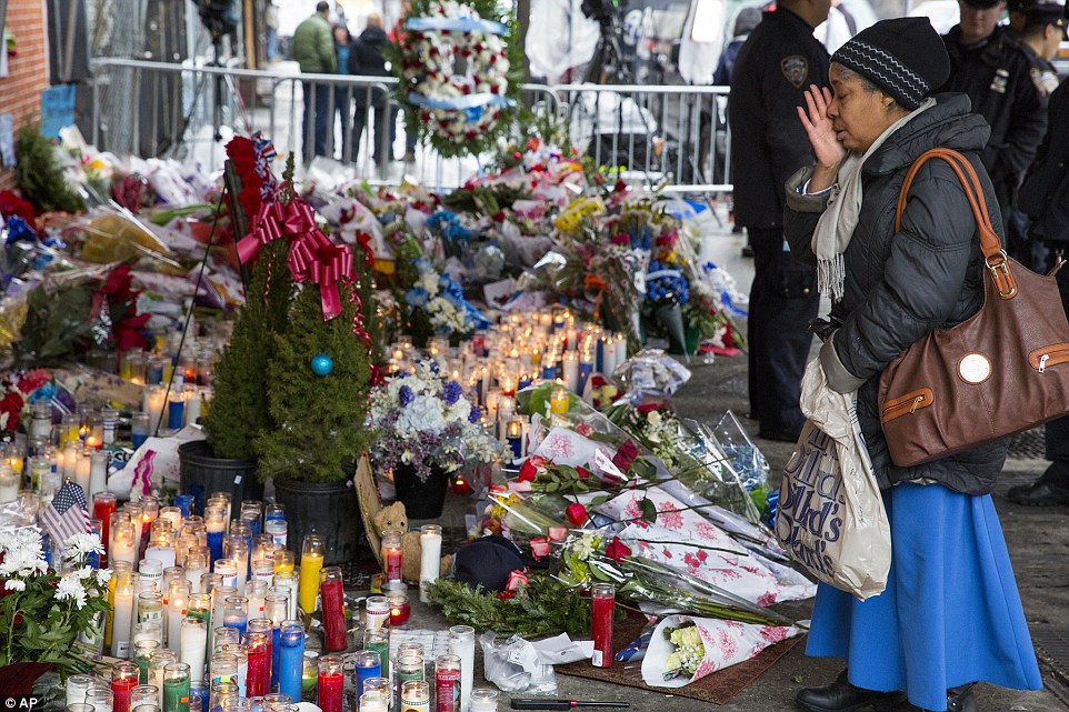 Overcome: A member of the public brings a hand to her face when confronted with the sea of flowers and candles gathered in Brooklyn