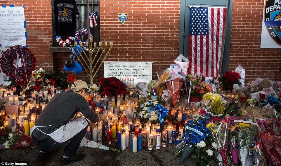 Lights in the dark: A man in a New York Yankees cap kneels down and lights another candle at the sad spot