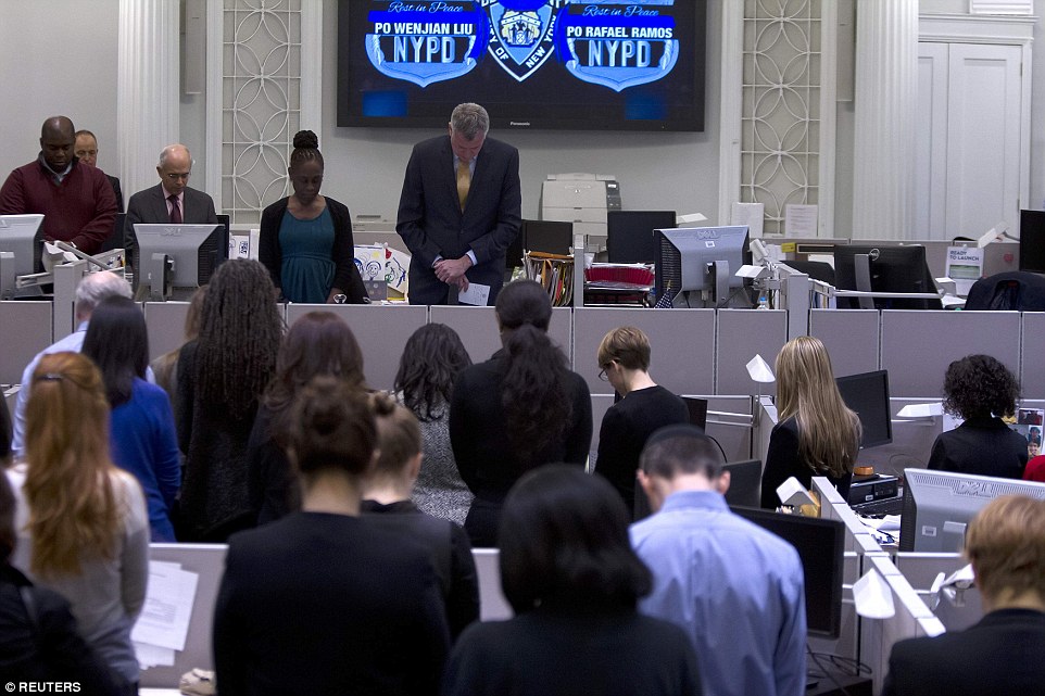 Silence: Mayor Bill de Blasio bowed his head in City hall - and urged others to do the same - at 2.47pm, the time the officers were shot