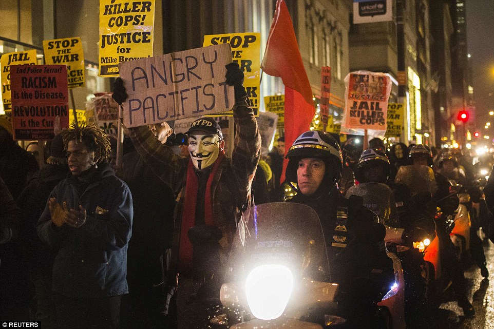 NYPD officers used motorbikes to create a cordon as protesters, demonstrating against decisions by grand juries in New York and Missouri not to indict white police officers in the killings of unarmed black men, held placards while marching down Fifth Avenue in Manhattan on Tuesday night