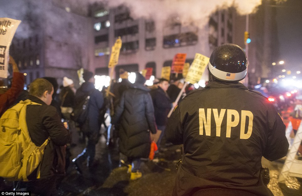 An NYPD Officer on a motorbike keeps track of anti-NYPD protesters as they march through the Upper East Side of Manhattan on Monday