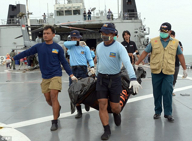 Indonesian Navy personnel carry a bag containing the body of a passenger of AirAsia Flight 8501 at sea off the coast of Pangkalan Bun