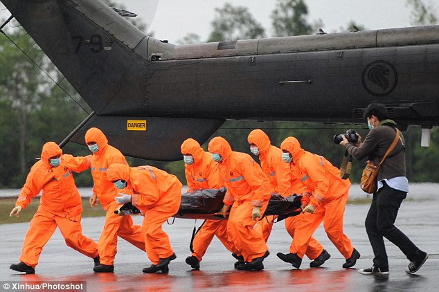 Search and rescue personnel carry a body bag containing a victim of the AirAsia flight QZ8501 at Iskandar Air Base in Indonesia 