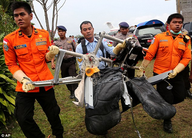 National Search and Rescue Agency personnel carry wrecked seats from the AirAsia plane to land