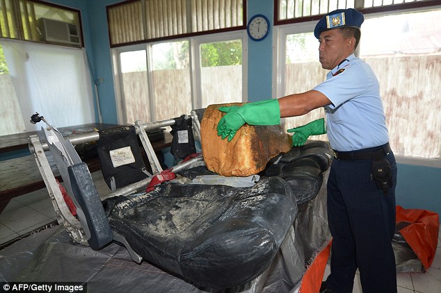 An Indonesian officer wears gloves as he handles the latest batch of wreckage found in the Java Sea