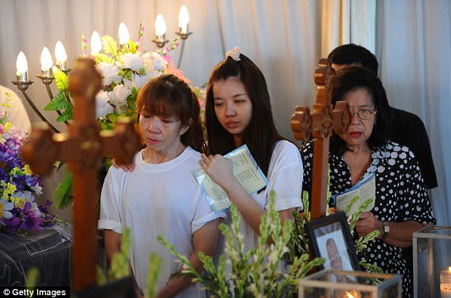 Relatives and friends pray during the funeral ceremony of crash victim Lim Yan Koen