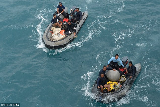 Indonesian navy divers arrive on their inflatable boats after conducting operations to lift the plane's tail