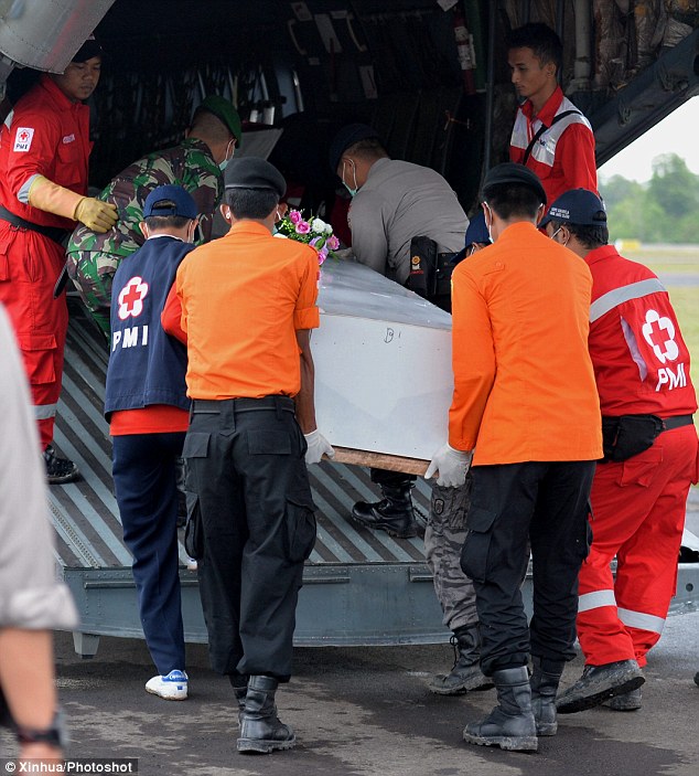 Rescuers carry a coffin containing the body of a victim, after AirAsia announced families of the victims will be offered $US100,000 in compensation by the airline 