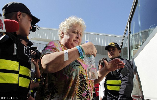 Support: A woman  carrying a water bottle is helped onto the waiting vehicle by police 