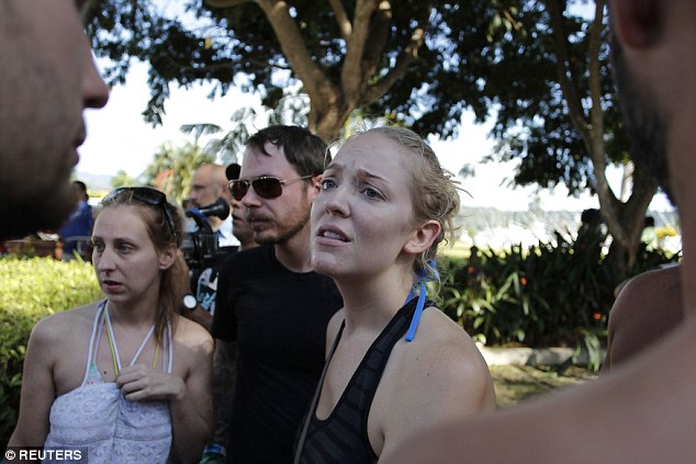 Safe: Passengers from the downed boat gather as they reach the shore. The vessel was carrying more than 100 people at the time 