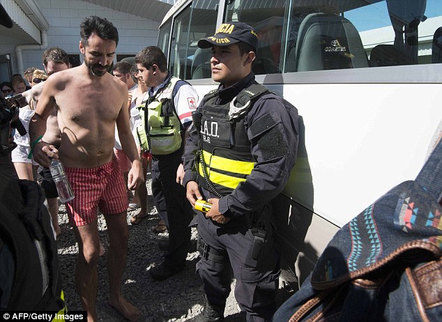 Transport: A man wearing his swimming trunks is led to the bus taking passengers back to their accommodation 