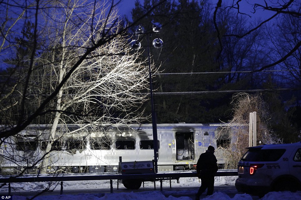 A police officer walks in front of a Metro-North train stopped on the tracks around 30 miles outside of New York City where it slammed into an SUV stuck on a crossing 