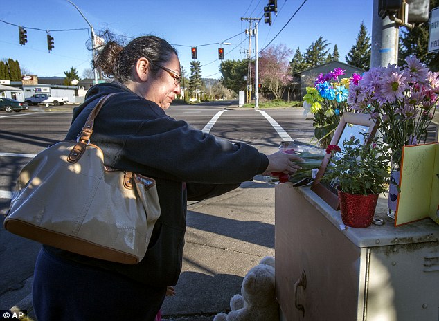 Emotional: Three children aged four to eight have been killed and their mother left critically injured after being struck by pickup truck while crossing a busy Oregon intersection, police have said. Above, Lisa Hurlimann pays her respects to the victims on Main Street at 54th in Springfield, where the youngsters were declared dead